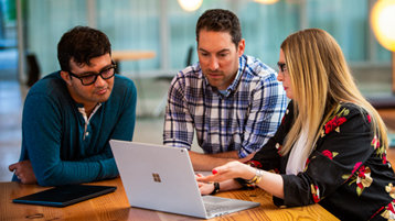 Team of professionals meeting and working around a Surface device.