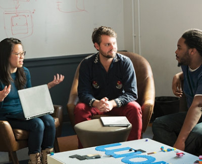 Three people sitting in chairs having a conversation.