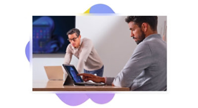 Two workers setting up a Teams video call in a meeting room.