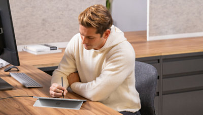 A person sitting at a table using a tablet.