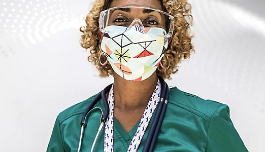 A healthcare professional wearing scrubs, a stethoscope, safety glasses and a mask.