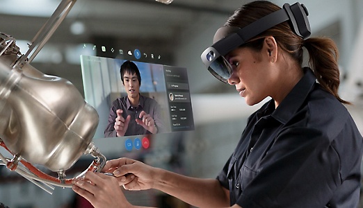 Eine Person führt eine Videounterhaltung über eine HoloLens 2, während sie an einem Gerät arbeitet.
