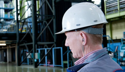 Ein Arbeiter trägt einen Schutzhelm und Ohrstöpsel.