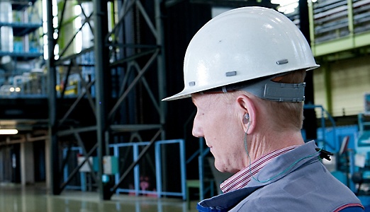 A worker wearing a protective hard hat and ear plugs.