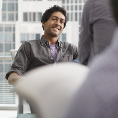 A person sitting in a meeting smiling.