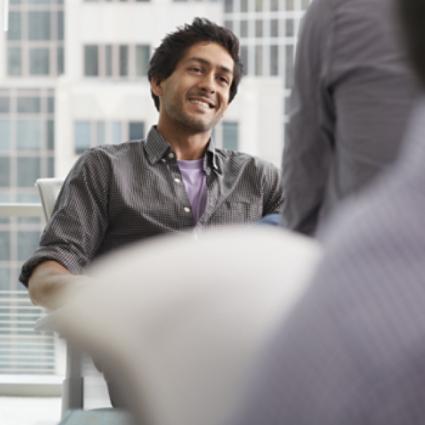 A person sitting in a meeting smiling.
