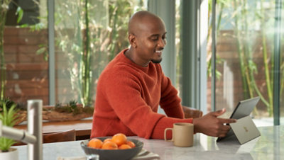 Personne assise dans une cuisine et utilisant une tablette