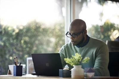 A person working remotely from their home office on a Surface laptop