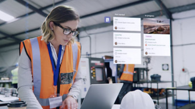A woman is working on a laptop in a factory.