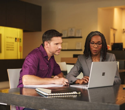 A man and woman looking at a laptop.