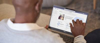 Person using a laptop with a social media profile visible on the screen.