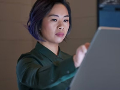 一位穿著綠色襯衫的女士拿著電腦。