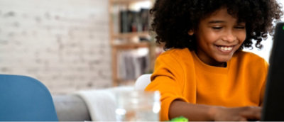 Person in a yellow shirt sitting at a table, indoors with a soft-focused background.