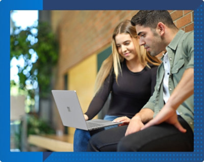 Two people sitting and looking at a laptop screen, engaged in discussion. 