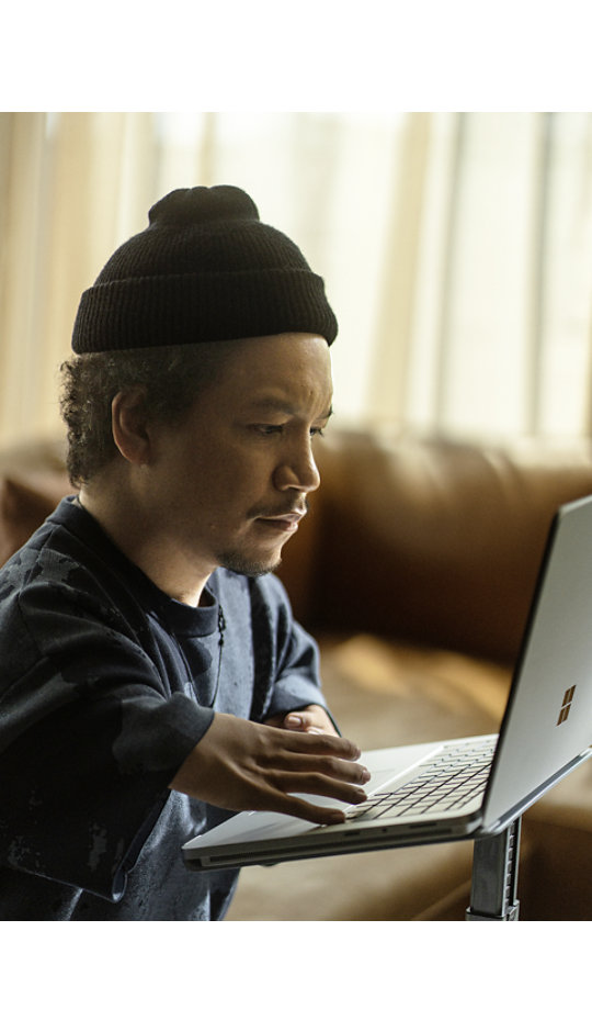 Surface Laptop Studio 2 でキーボードを操作するビーニー帽を被る若い男性。