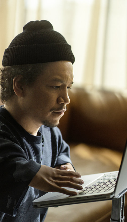 Young man wearing a beanie interacts with the keyboard on his Surface Laptop Studio 2.