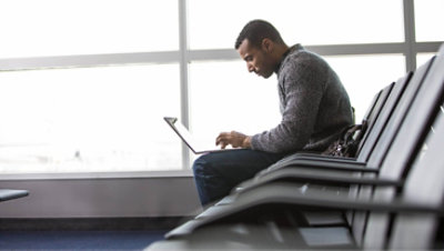 A person working in an airport on a laptop.