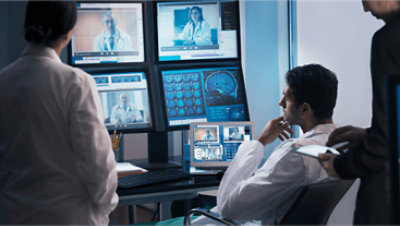 Three people around a desk watching videos of other medical professionals