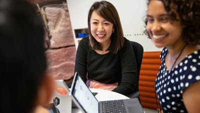 坐在放着笔记本电脑的桌旁的人在对话和大笑