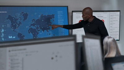 指向墙上的世界地图并与同事交谈的人