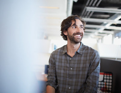 Person presenting a complex diagram on a whiteboard to an audience, holding a laptop with various stickers.