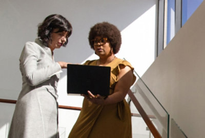 兩名女孩站著，討論自動化行銷如何與膝上型電腦配合使用