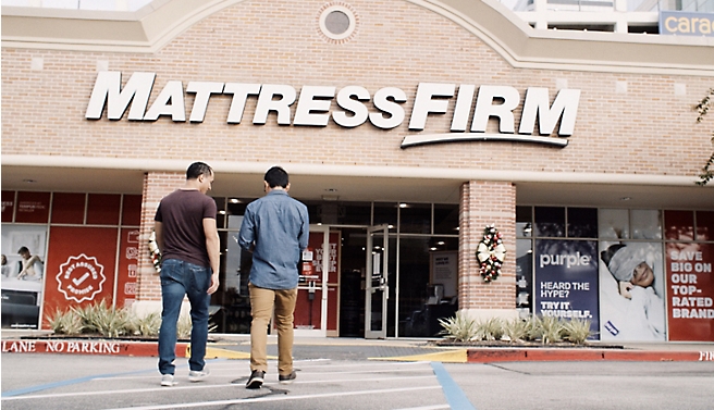 Δύο άνδρες στέκονται μπροστά από ένα κατάστημα εταιρείας στρωμάτων.