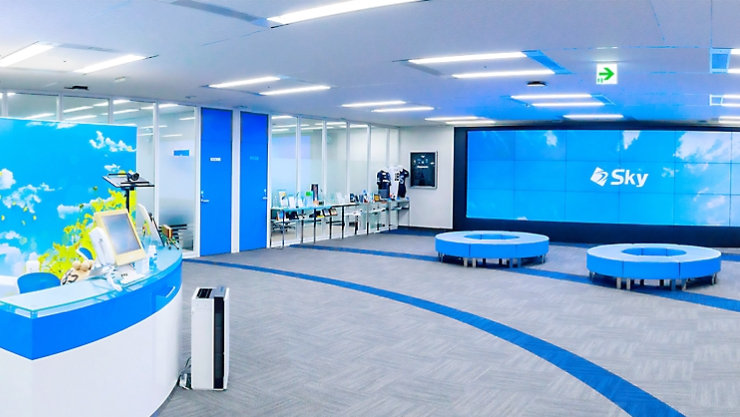 Skyのロゴが表示された、青を基調としたモダンなオフィス空間。