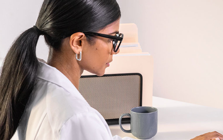 female doctor reading from her phone with her laptop open behind the phone