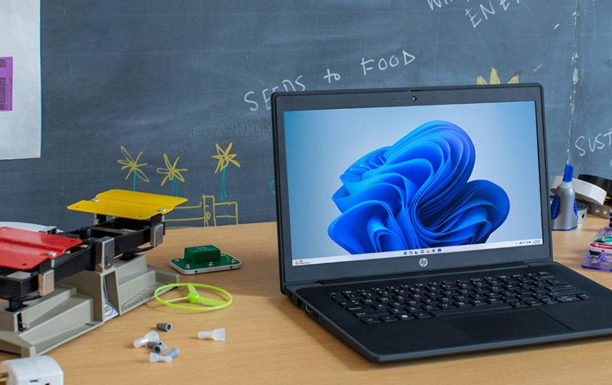 The laptop screen shows the Windows 11 bloom in light mode. Education collection shown.