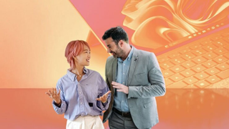 Zwei Personen unterhalten sich lächelnd, im Hintergrund ein Laptop mit Windows-Logo. Warme Orange- und Rosatöne.