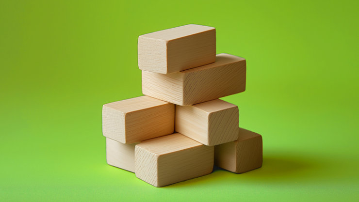 Wooden blocks stacked in a pyramid shape against a green background.