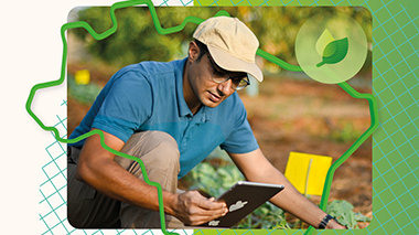 Pessoa com boné usando tablet em plantação com ícone de sustentabilidade.