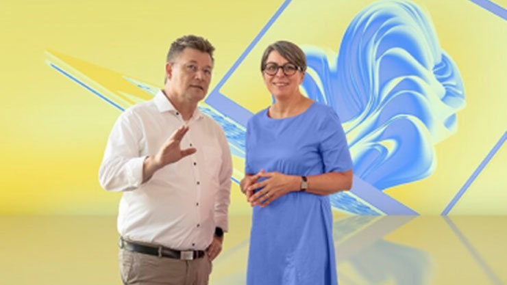 Zwei Personen, ein Mann und eine Frau, stehen vor einem gelben Hintergrund mit blauen, abstrakten Formen, die einen Laptop darstellen.