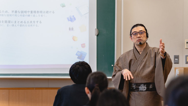 教室でプレゼンテーションを行う登壇者と、説明を聞く参加者の様子。スクリーンに資料が映し出されている。
