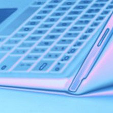 「角度をつけて開かれたノートパソコンのキーボード部分をクローズアップした青みがかった描写」