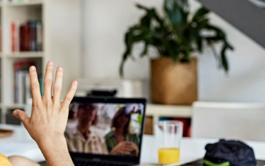 A person wearing hearing aids communicating to two individuals through a video call.