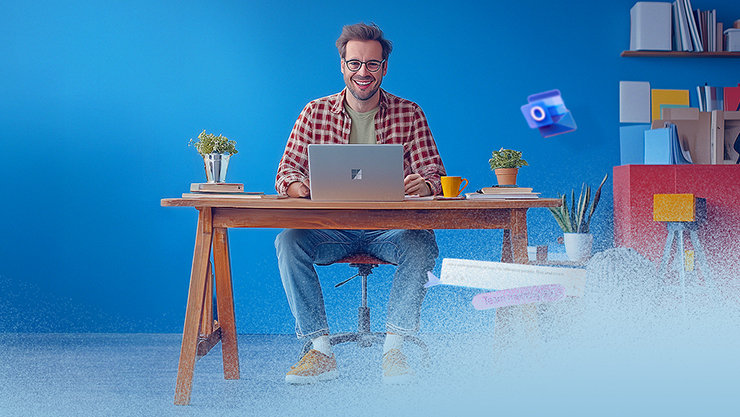 Mann sitzt am Schreibtisch mit aufgeklapptem Surface Laptop, blauer Hintergrund