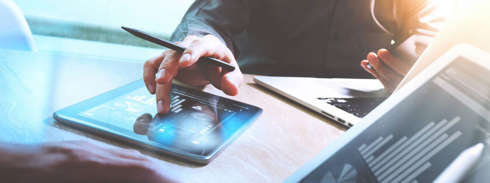 Mensch an Schreibtisch mit Tablet, Smartphone und Laptop