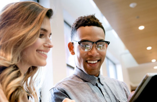 Eine Frau und ein Mann im Gespräch, sie halten ein Tablet in Händen.