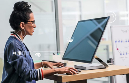 Frau, die im Stehen am Surface Studio kreativ arbeitet