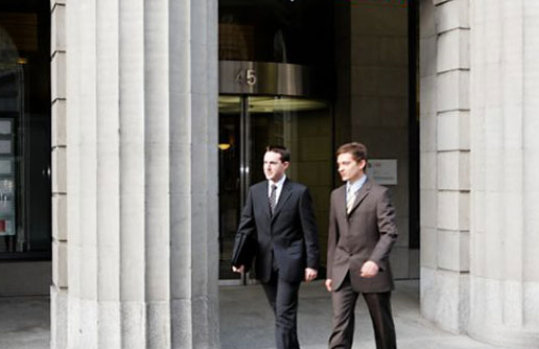 Foto von drei Personen, die vor dem UBS-Gebäude entlang laufen