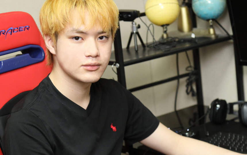 染めた髪の男が自分のワークステーションに座っている