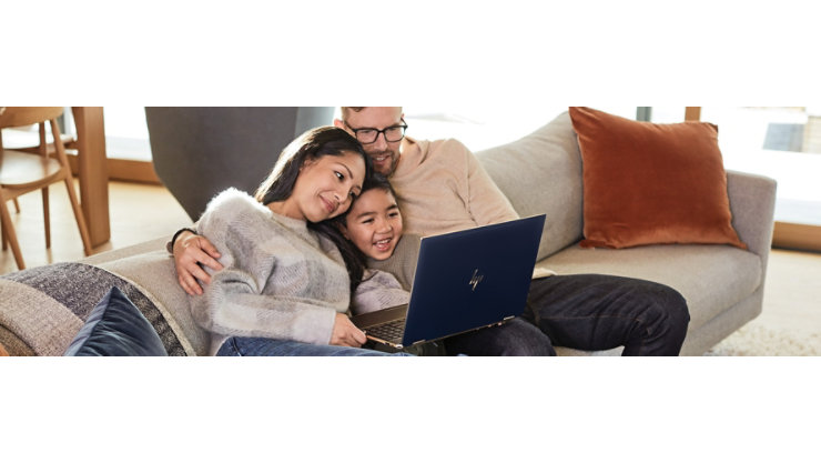 ソファで 1 台のノート PC の画面を見る家族