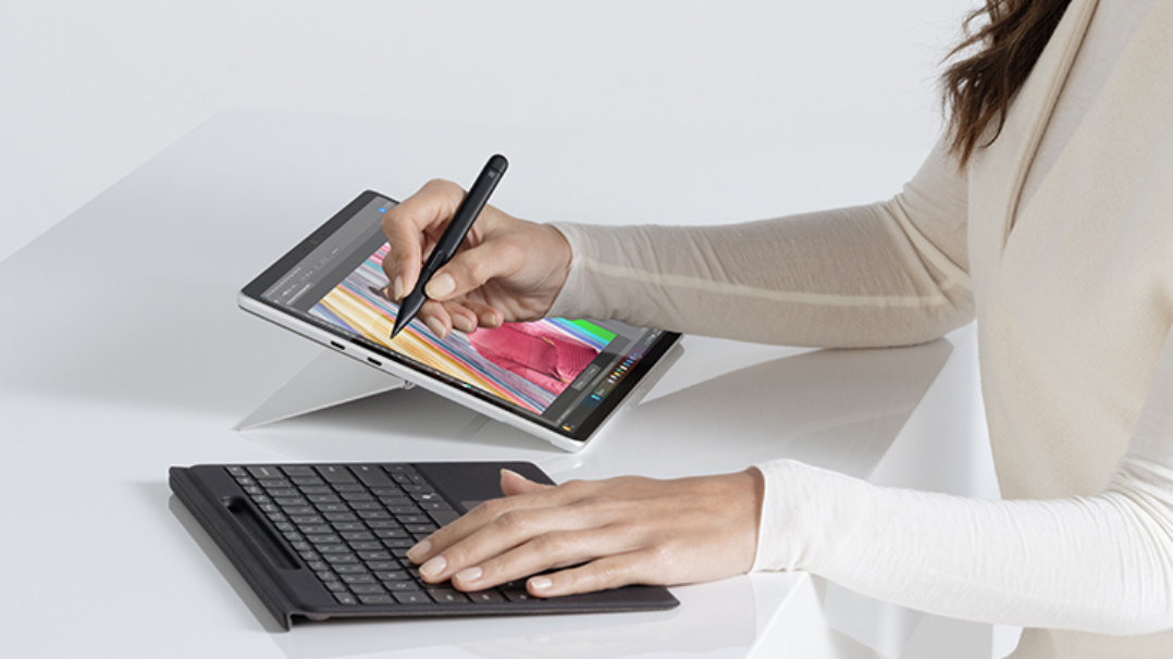 女性が Surface Pro デバイスでスタイラスとキーボードを使用しています。