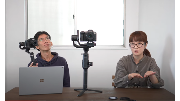 1 人の女性、1 人の男性、1 台のコンピューター、1 台のカメラのポートレート