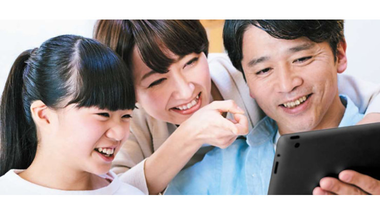 タブレットでビデオを見ながら笑っている 3 人家族