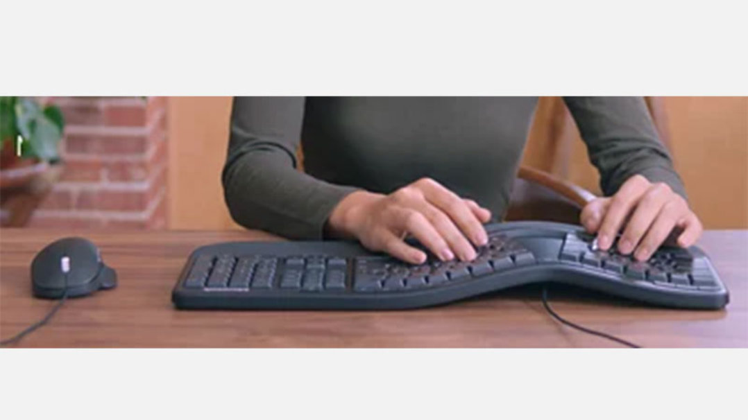 机の上に置かれたキーボードを使用している人