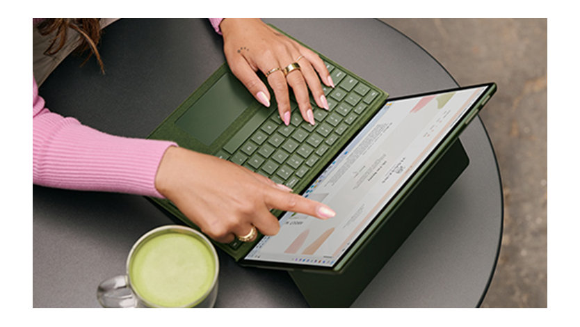 Surface Pro 9 の画面にタッチしながら外で作業する女性