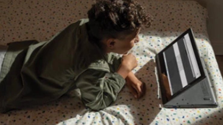 Eine Person liegt vor einem offenem Surface und blickt auf den Bildschirm.